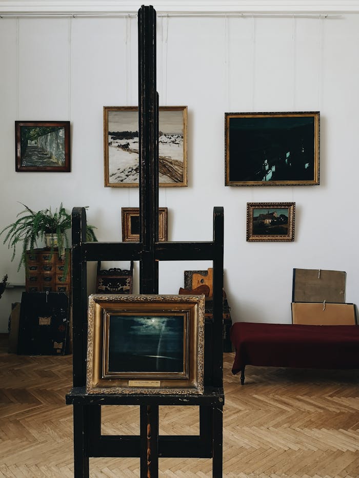 Explore an elegant art gallery interior showcasing various framed paintings and a wooden easel.