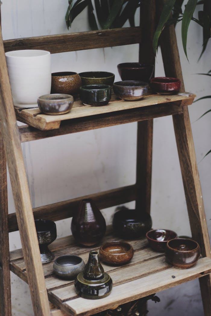 A collection of handmade pottery arranged on rustic wooden shelves, showcasing artistic earthenware.