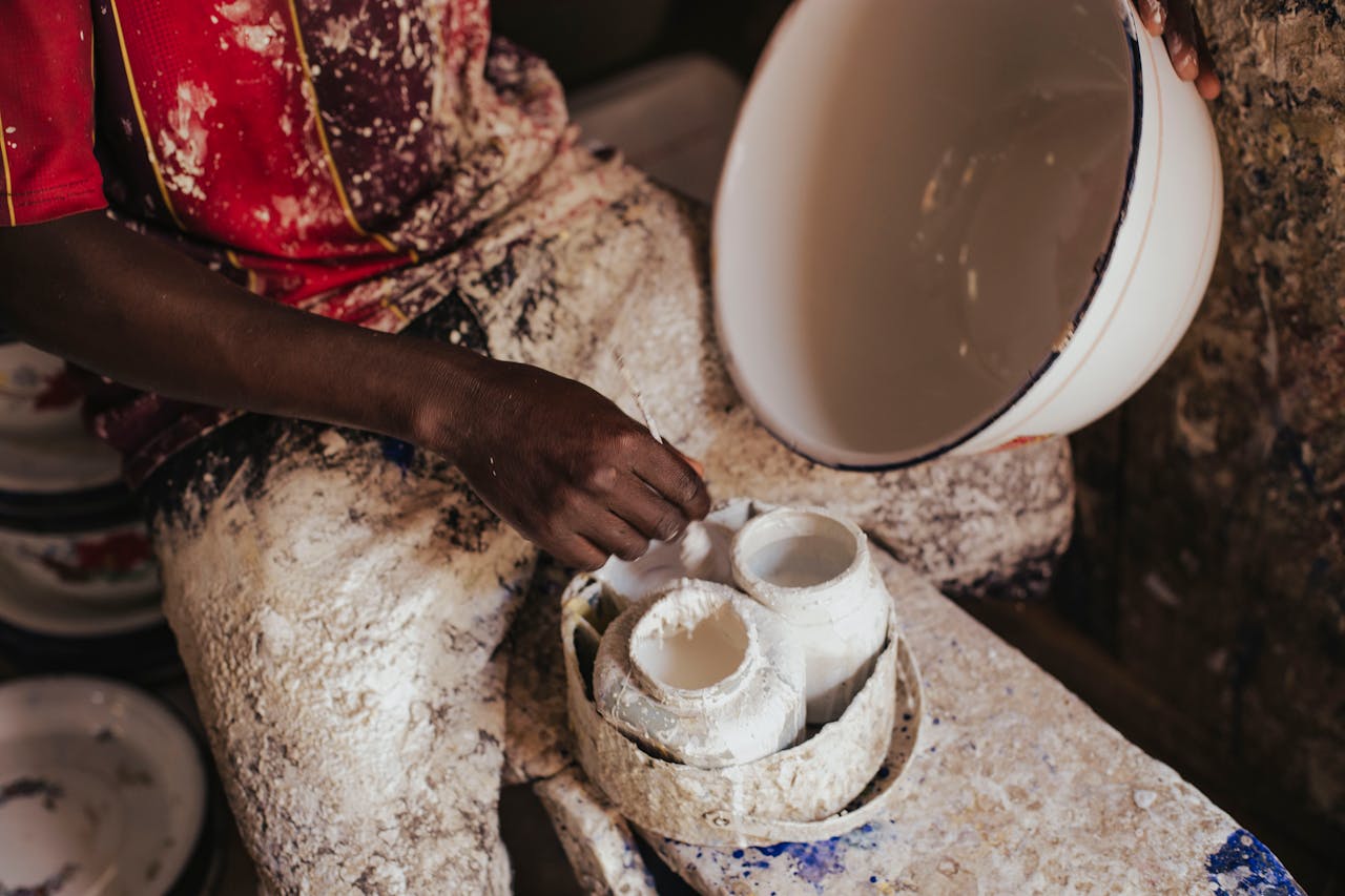 A skilled artisan in Kano, Nigeria, carefully crafting ceramic pieces by hand, showcasing traditional artistry.