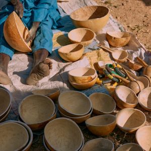Authentic Nigerian artisan crafting calabash bowls outdoors, showcasing traditional craftsmanship and cultural heritage.